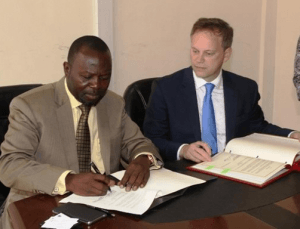 Dr Dominic Akuritinga Ayine, Deputy Attorney-General  signing the document with  Dr Grant Shapps, Minister of State, Foreign and Commonwealth.