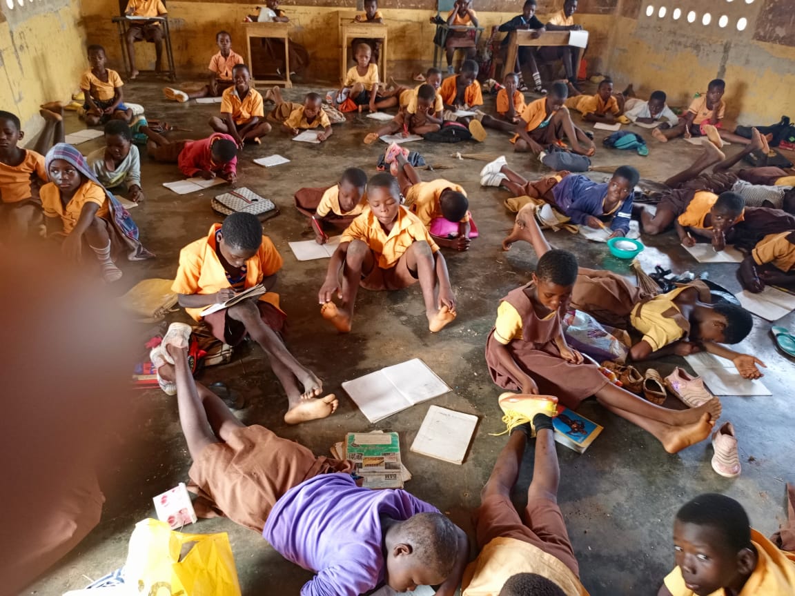 School children in Babile D/A Primary lie on floor to write